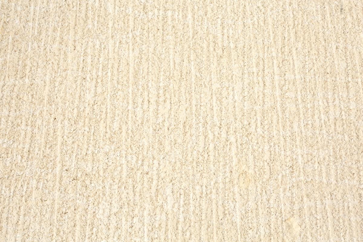 Gros plan sur la texture d'un tapis en laine à poils hauts, ton neutre crème