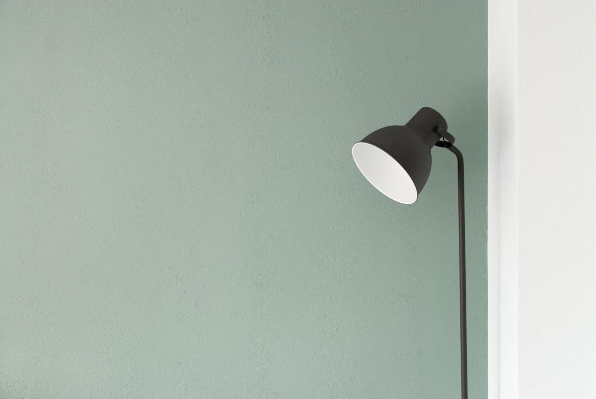 Lampadaire noir fin éclairant un coin de pièce