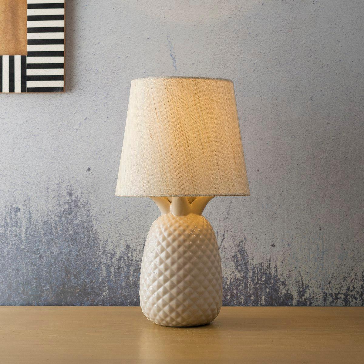 Lampe à poser en céramique crème avec abat-jour, lumière chaude sur un meuble en bois