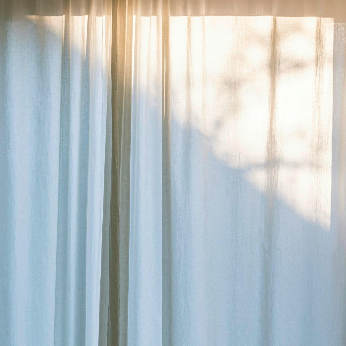 Rideau en lin blanc voile diffusant une lumière chaude de fenêtre