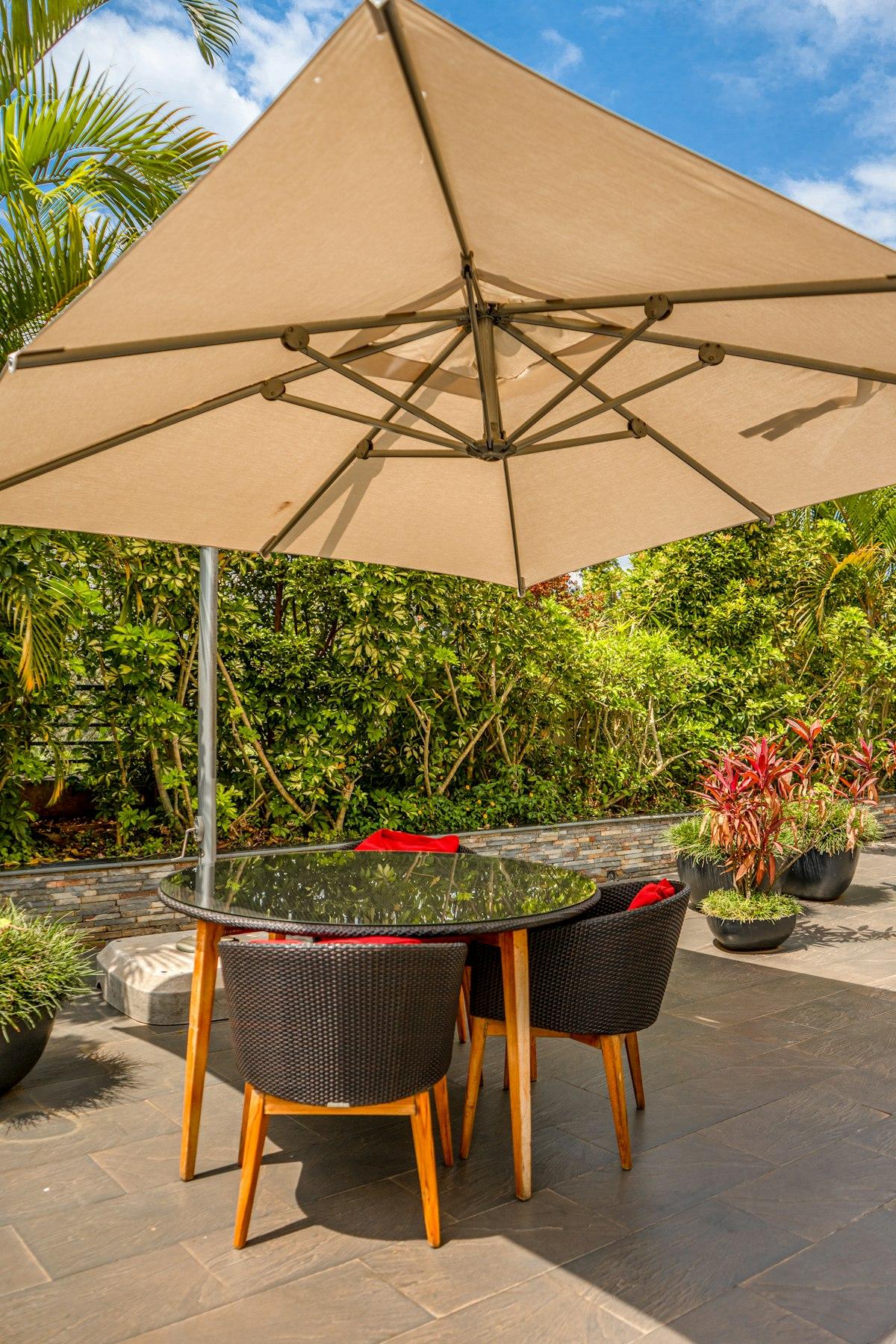 Parasol déporté dont le mât latéral ombrage une table de repas extérieure