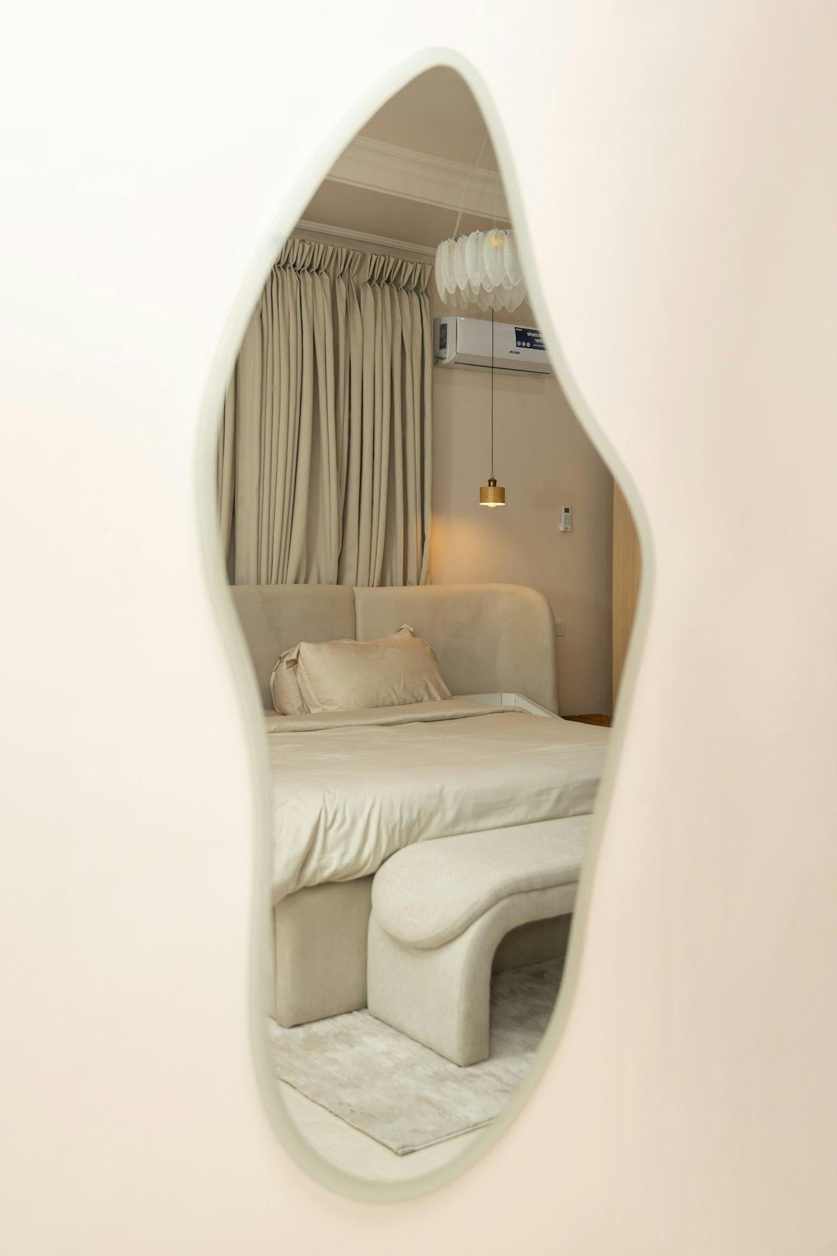 Miroir à la forme organique irrégulière reflétant une chambre